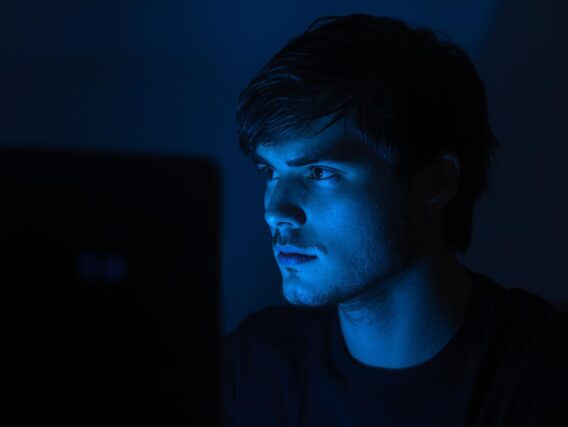 Pessoa mexendo no computador e recebendo a luz azul no rosto